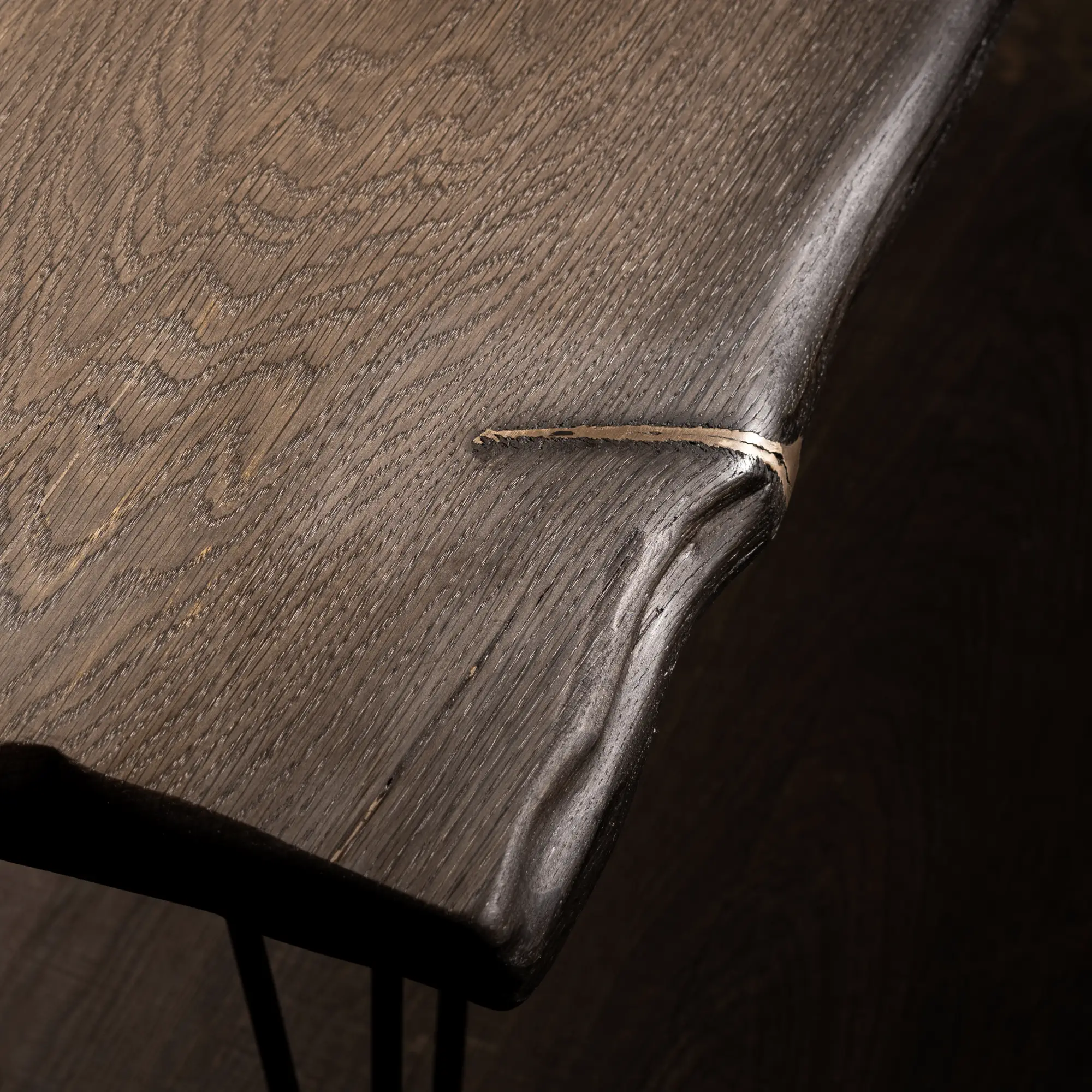 Detail einer Tischplatte aus Mooreiche mit einer Intarsie aus Metall